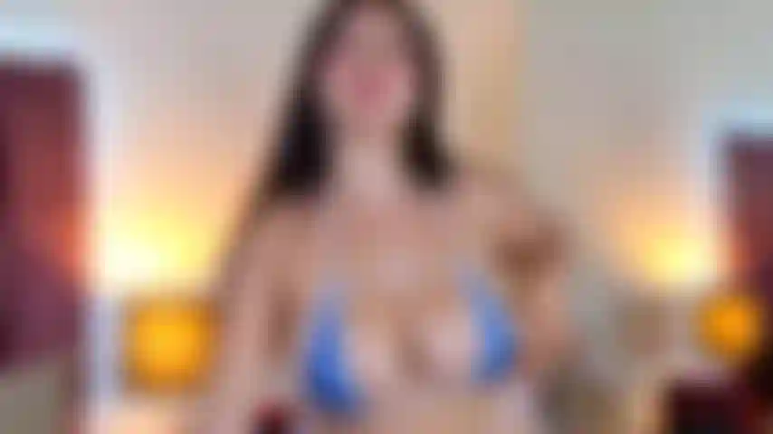 Langsam entblößt sie ihre brüste und spielt provokativ mit ihrer zunge auf eine feuchte und kokette weise. Mit einem verführerischen blick streckt sie ihre beine aus, um sie in ihrer ganzen länge zu zeigen – glatt und gepflegt.
