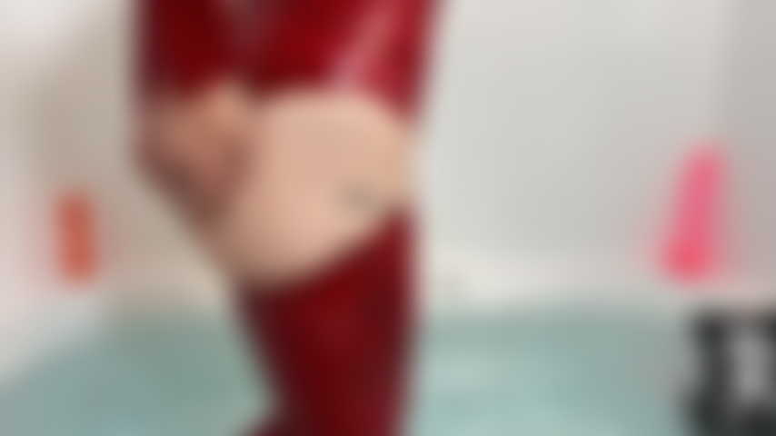 Rotes latex-outfit im bad, necke und spiele mit muschi, kapuze