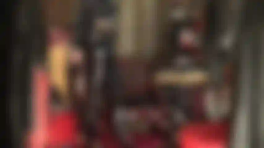 Pvc-fetischistin – komplett in glänzendes schwarzes vinyl gekleidet, die herrin neckt den pvc-fetischisten mit glänzenden jeans, absätzen und einem langen mantel.