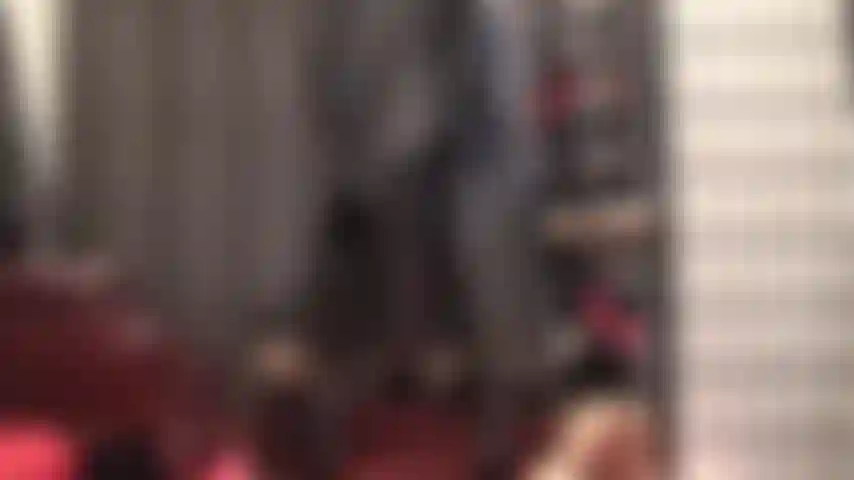 In leder gekleidete göttin, die mit ihrem perfekten hintern, geschmückt mit einem langen schwarzen ledermantel, verführt.