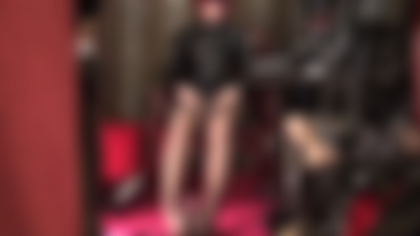 Herrin streichelt zwei schwänze – gekleidet in glänzendes pvc und braune strumpfhosen, ihre füße sind um den schwarzen schwanz geschlungen, während die herrin ihren weißen strap-on mit bloßen händen streichelt.