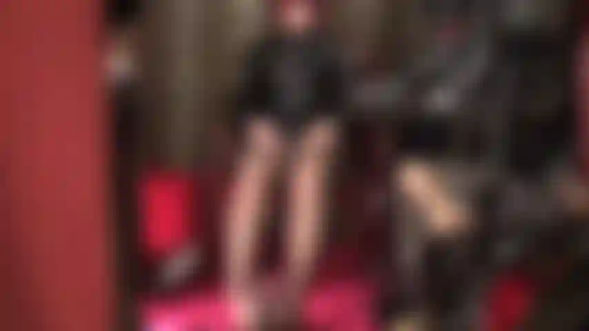 Herrin streichelt zwei schwänze – gekleidet in glänzendes pvc und braune strumpfhosen, ihre füße sind um den schwarzen schwanz geschlungen, während die herrin ihren weißen strap-on mit bloßen händen streichelt.