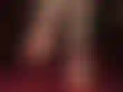 Ein barfußfetischist in roten stilettos mit fesselriemchen, baumelnd.