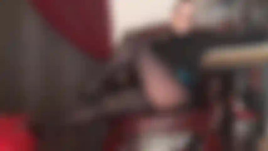 Herrin verführt mit ihren beinen in schwarzen hochglanzstrumpfhosen und einem sexy dekolleté im spitzen-bh.