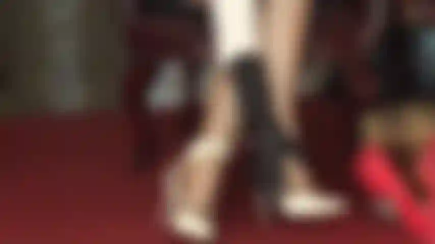 Die weiße riemchensandalen und glänzende strumpfhosen trägt und die füße neckt.