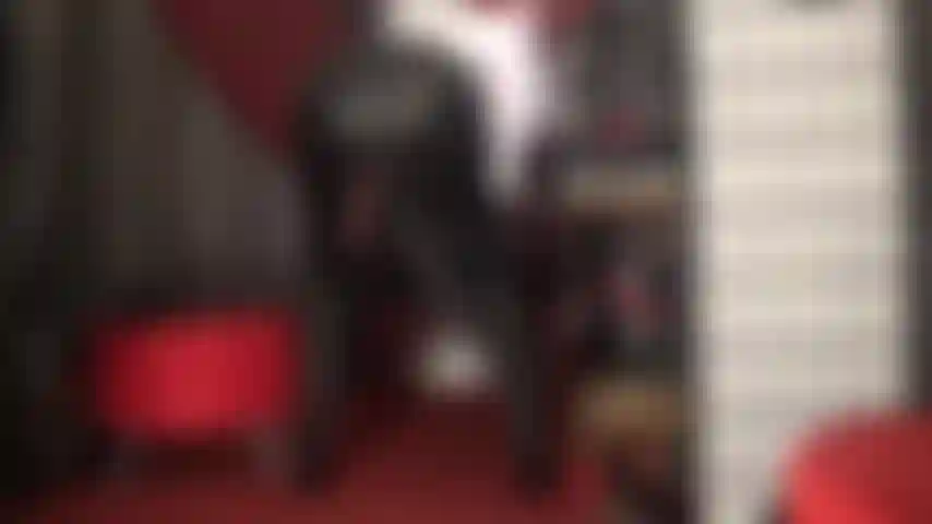 Sie verspottet sie mit ihrem riesigen schwarzen schwanz, der von ihrem lederrock baumelt.