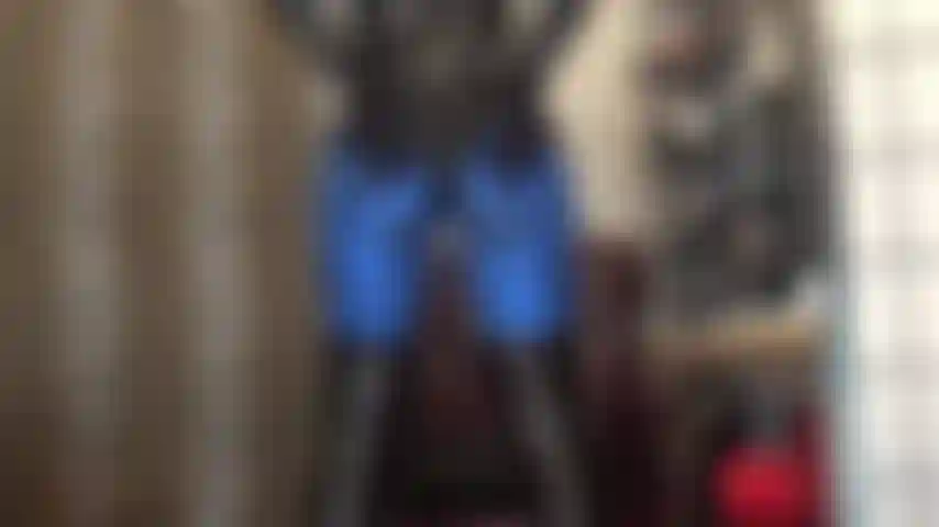 Hintern in blauen metallic-lycra-leggings und glänzendem pvc-bodysuit, füße in dunkelbraunen strumpfhosen.