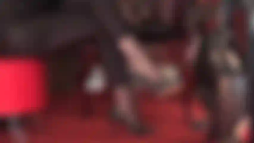 Genießen sie diese seitenansicht schwarzer lederpumps, die in strumpfhosen und glänzenden spandex-leggings baumeln.