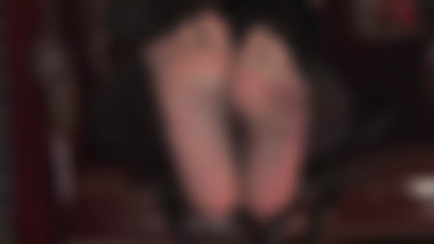 Sexy füße wackeln in schwarzen, durchsichtigen strumpfhosen und necken den fußsklaven.