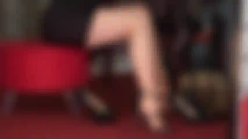 Verführerische beine und füße in sonnengebräunten strumpfhosen und mehreren paar sexy schwarzen high heels.