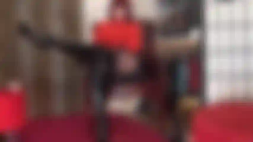 Die ihren körper in diesem sexy outfit aus rotem bodysuit, glänzendem vinylrock, schwarzen strumpfhosen und hohen overknee-stiefeln aus schwarzem lackleder verehrt.