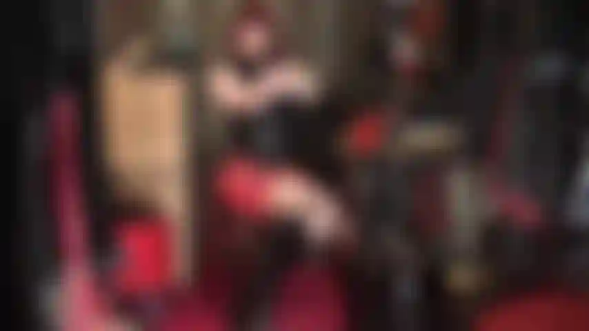 Latexfetischistin – rot-schwarzes gummioutfit mit kniestiefeln.