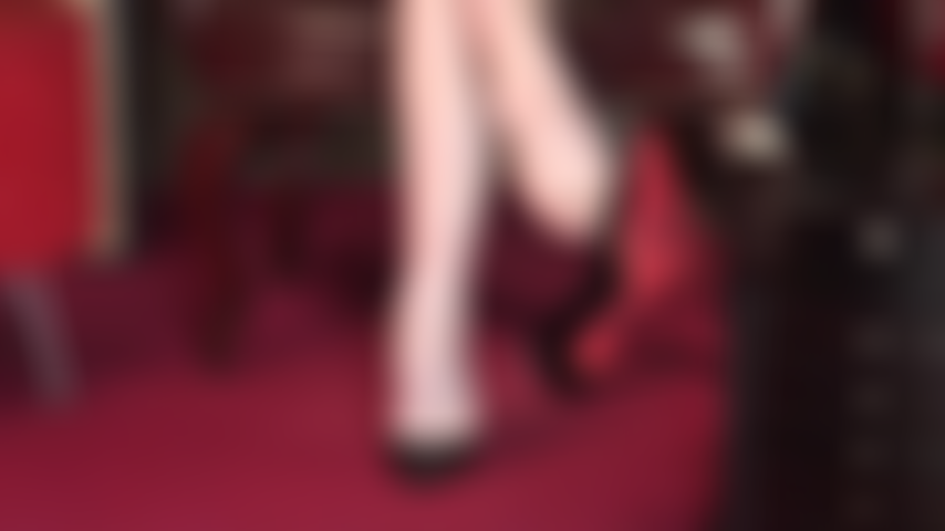 Hübsche nackte füße, an denen pumps mit roten sohlen baumeln.