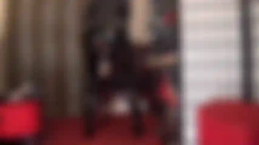 Eine pvc-göttin in einem glänzenden schwarzen catsuit, die mit ihrem riesigen weißen strap-on-schwanz neckt, der unter ihrer rockschicht hervorschaut.