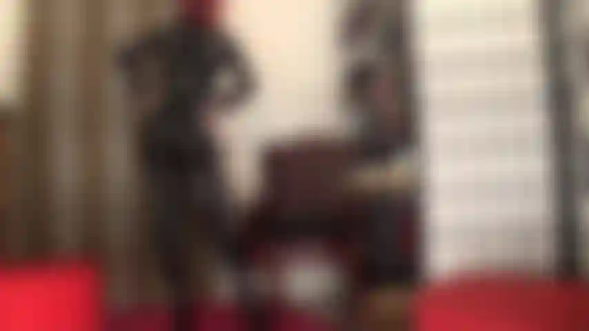 Eine göttin der anbetung in einem engen schwarzen pvc-catsuit, einem korsett und overknee-stiefeln.