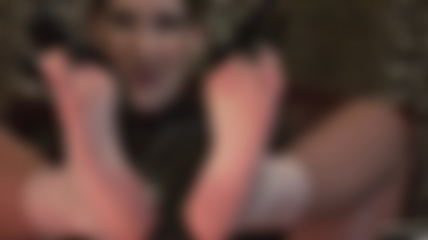 Barfußfetisch und latex – herrin neckt den fußliebhaber mit ihren weichen nackten füßen und schwarzen glänzenden latexhandschuhen.