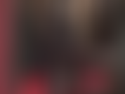 Eine versaute latex-fetisch-göttin im schwarzen gummi-catsuit mit kapuze und bbc-strapon.