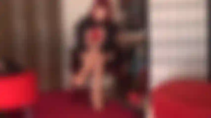 Verführerisch in rot – herrin vivian schlüpft in ein paar rote spitzenstrümpfe über glänzende hautfarbene strumpfhosen, rote stilettos und rote lederhandschuhe.