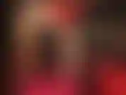 Sinnliche neckereien und körperanbetung in rot und schwarz – die herrin trägt ein sexy kleid mit lederkorsett, hautfarbene glänzende strumpfhosen und glänzende rote pumps.