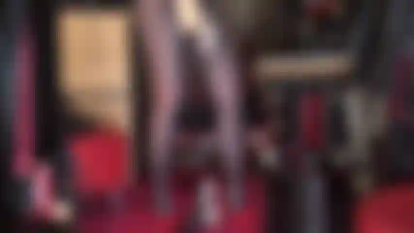 Eine satingöttin in strumpfhosen mit großem schwanz – schimmernde goldene satinbluse und passende handschuhe, die einen großen, schönen strapon-schwanz streicheln, seidige nylonbeine und heiße rote absätze.