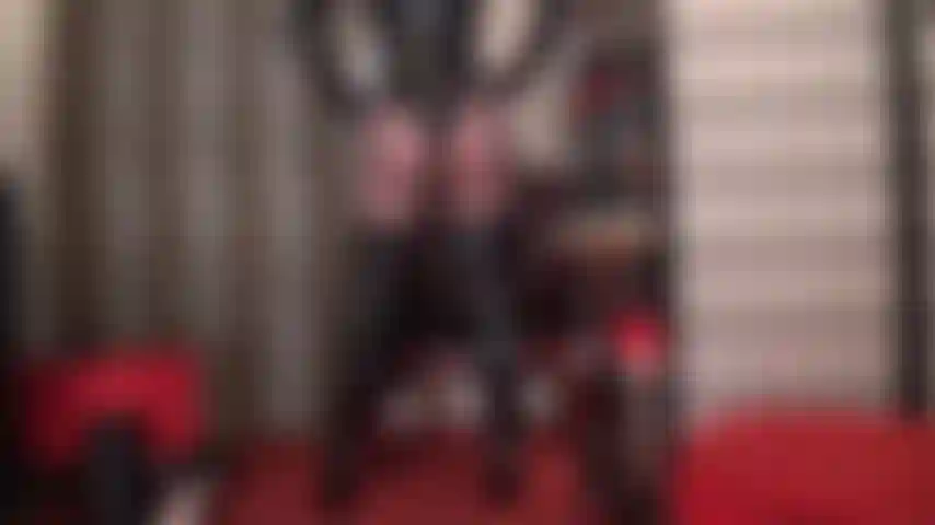 Glänzende kurven der perfektion – eine glänzende verführerin zeigt ihre perfekten kurven in einem string-lack-bodysuit, hohen overknee-stiefeln und hauchdünnen schwarzen strumpfhosen.