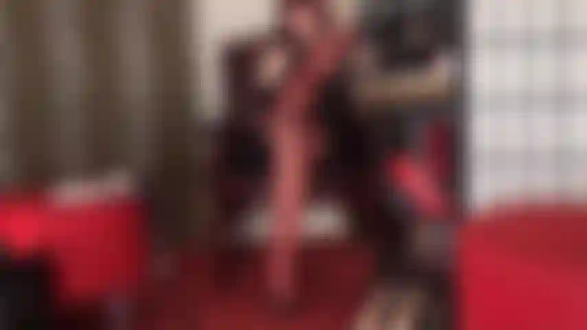 Eine strumpfhosenverführung in glänzenden roten nylonschichten und lederpantoletten mit hohen absätzen.