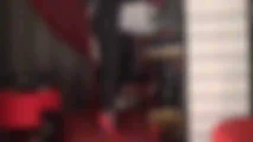 Rote fetisch-stilettos und ein roter spitzenstring auf einem engen schwarzen catsuit.