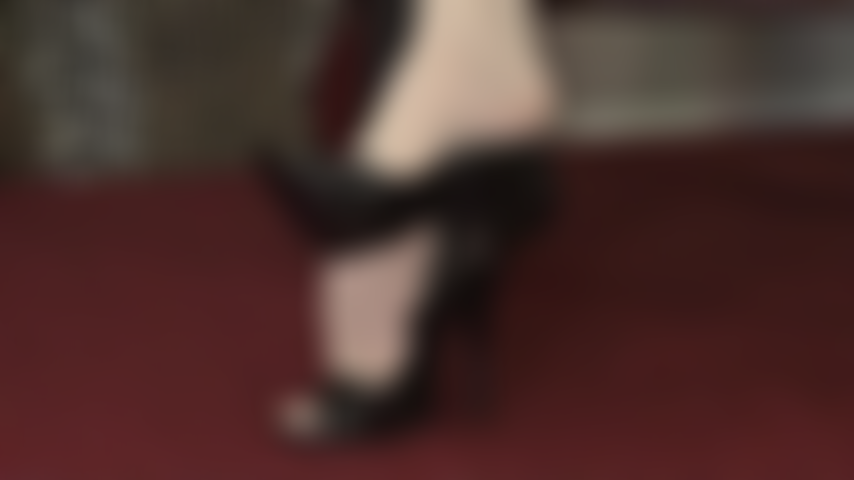 An den füßen blickdichte elfenbeinfarbene strumpfhosen, hübsche peeptoes und lederpumps baumeln.