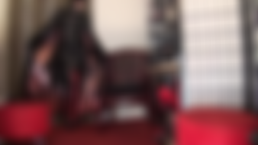 Der wahrgewordene traum eines jeden fetischliebhabers – die herrin ist vollständig in glänzendes schwarzes pvc, lederhandschuhe und hohe schnürstiefel gekleidet.