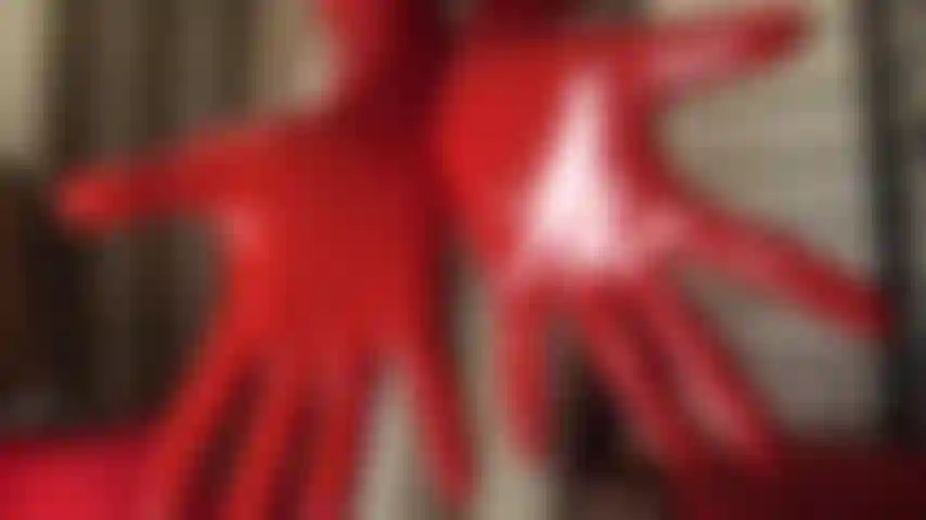 Gummifetischistin – herrin vivian trägt enges latex, einen kurzen rock über glänzenden strümpfen, handschuhe und eine komplette gummihaube.