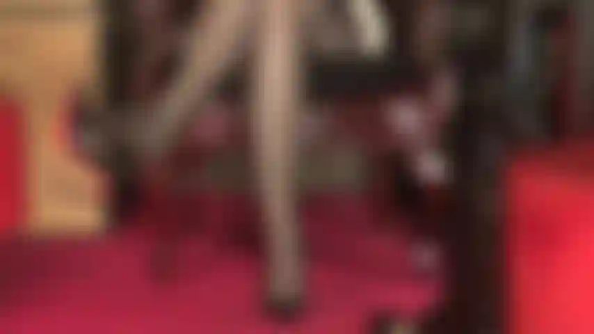 Ein sexy blick auf in strümpfe gehüllte beine, ein strumpfhalter mit mehreren riemen, sexy übereinandergeschlagene schenkel und zehen, an denen ein pumps mit roter sohle baumelt.