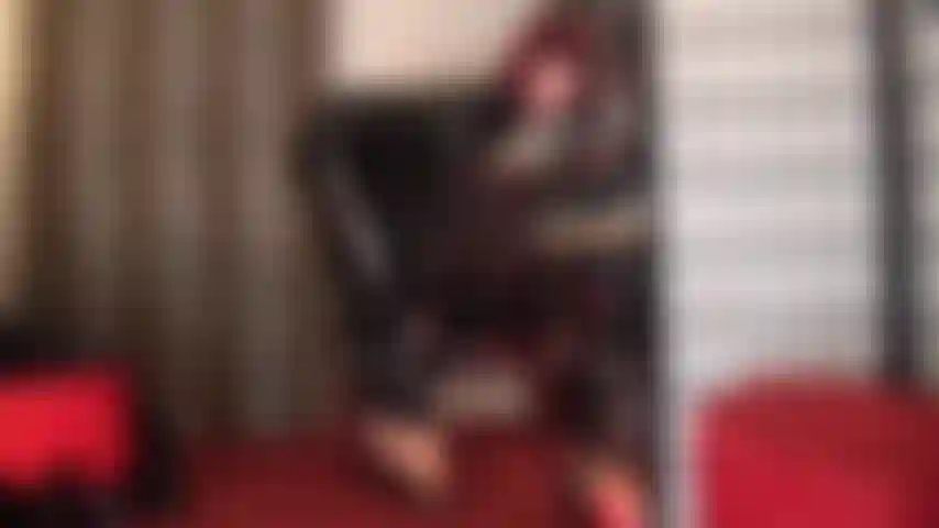 Ein glänzender schwarzer lack-catsuit und sexy pantoletten mit hohen absätzen – ihre göttin neckt mit ihren unglaublich hohen fußgewölben in absätzen und strumpfhosen und gewährt verstohlene einblicke in das, was sich unter dem anzug befindet.