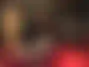 Herrin hockt und zeigt ihren tollen hintern und ihre hüften in einem glänzenden schwarzen pvc-tanga-bodysuit und einer durchsichtigen strumpfhose mit leopardenmuster und neckt den schwanz.