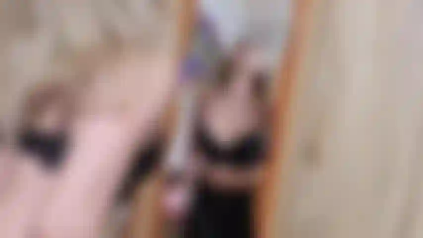 Eine versaute, freche blondine, die in leder gekleidet auf den spiegel spuckt und mit spucke spielt.
