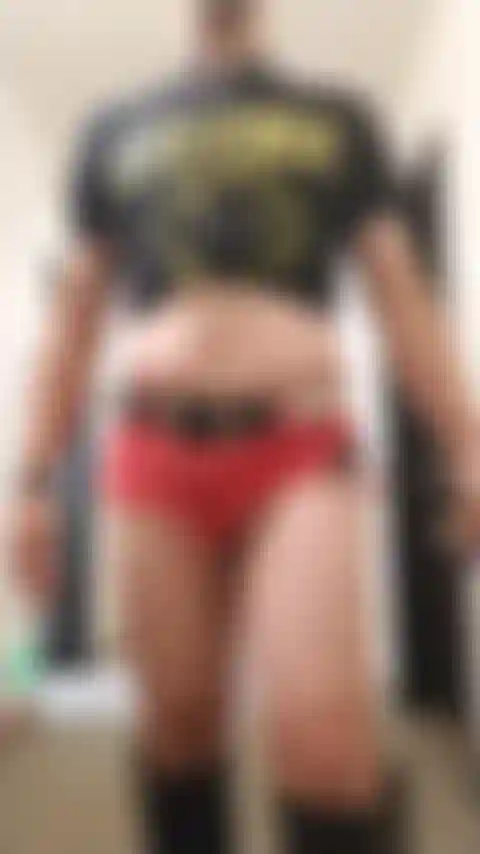 Ein crossdresser, der in jeansshorts und stiefeln sexy im hotelflur posiert.